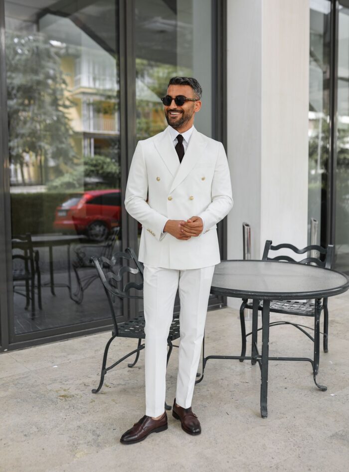 Seekers End Tailored slim fit white double breasted men's suit with peak lapels with decorative gold buttons.